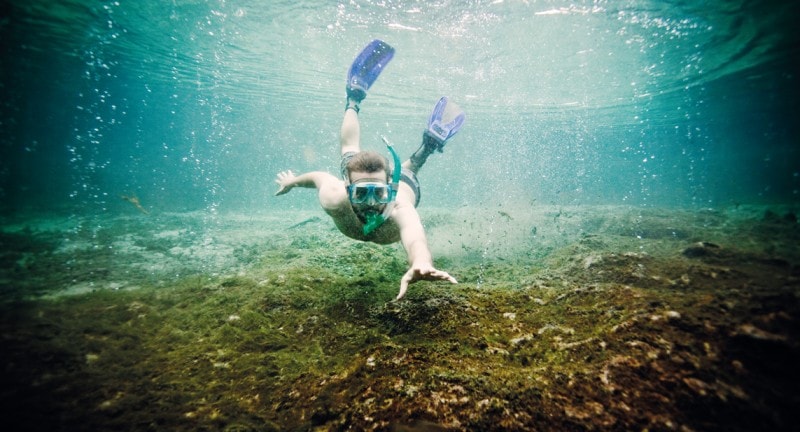 snorkelling man reaches out to the camera