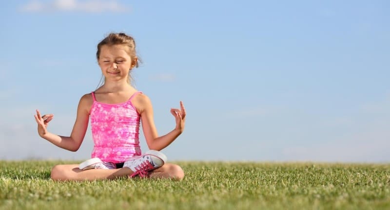 child doing yoga outside on the grass