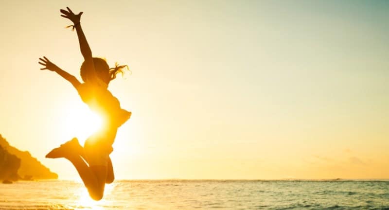 Girl jumping mid air behind a sunset