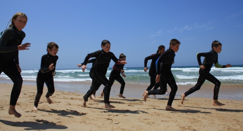 Kids in wetsuits on a beach in portugal