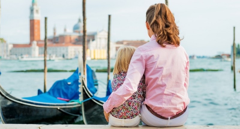 Mother and daughter sitting on a pier overlooking Venice