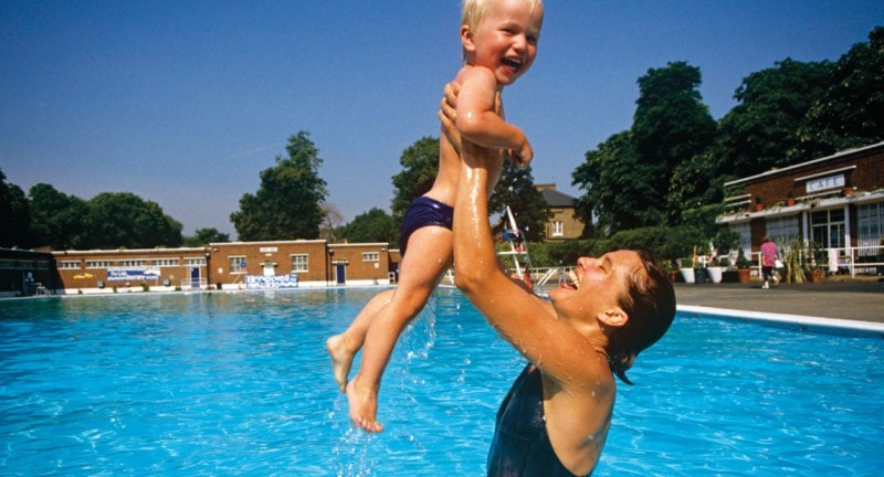 a mother and young son play in a london lido swimming pool