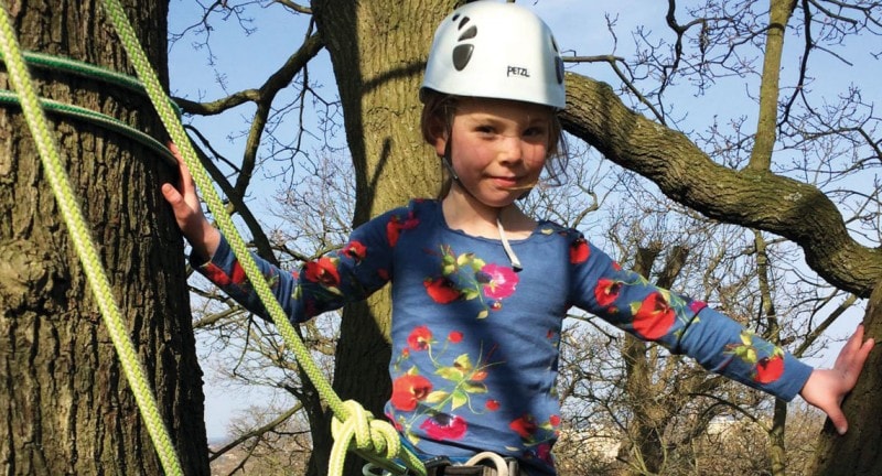 child in harness climbs a tree in london