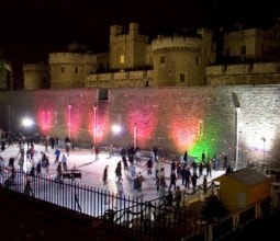 people ice skating after dark at the tower of london