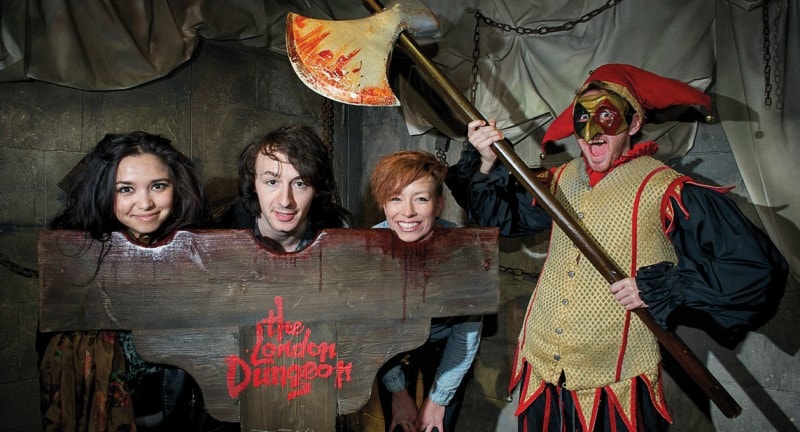 children with their heads in a block enjoying london dungeons
