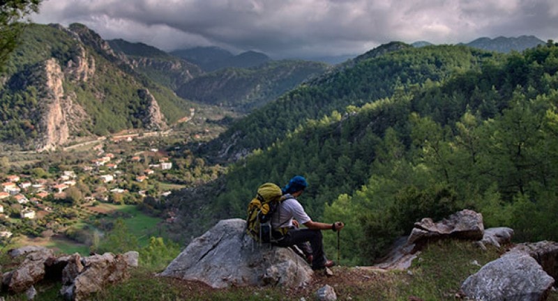 male hiker sits on rock at carian trail in turkey