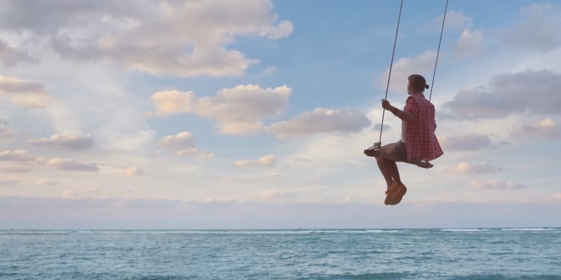 Girl swinging across ocean