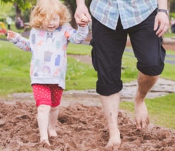 little girl walking barefoot hand in hand with her father