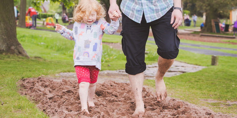little girl walking barefoot hand in hand with her father