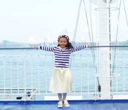 A girl in a stripy top and metallic skirt on the deck of a ferry in Portsmouth Harbour