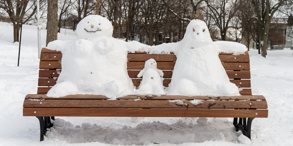 family winter breaks Montreal park bench with snowman family 