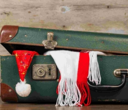 Closed suitcase with a Christmas hat and scarf on a wooden background old surface.