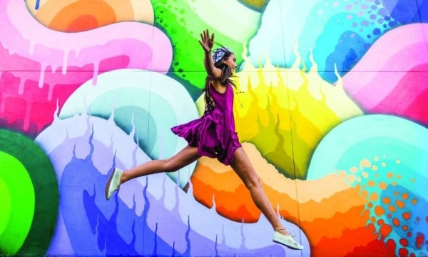 girl jumping in front of colourful painted wall