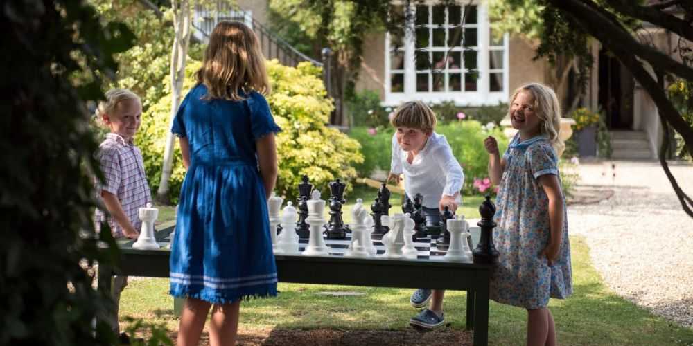 Dorset with kids children playing chess in garden of Eastbury Hotel